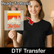 A smiling woman in a black shirt holds an InkMerge Retro Mountain Landscape 'The Veil' premium DTF transfer, featuring mountains, trees, and “Last Trail Before The Veil” text with an arrow. Above her is the text “Ready To Press.”.