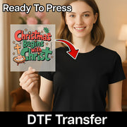 A smiling woman in a black shirt holds an InkMerge “Christmas Begins With Christ” DTF transfer, featuring festive colors, stars, and a cross. An arrow points to her shirt. Text: Ready To Press Heat Press Transfer.
