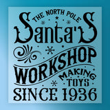 The North Pole Santa's Workshop Design by InkMerge is a decorative DTF transfer with ornate fonts, snowflakes, and swirls on blue—precut and ready to press for easy holiday crafting.