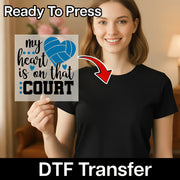 A smiling woman holding a sign with the text "my heart is on that court" and a red arrow pointing to her chest.