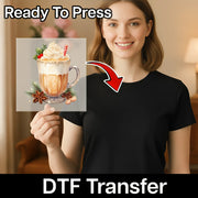 A smiling woman holds a black shirt with the Festive Holiday Beverage Design by InkMerge, showing a whipped cream-topped drink, holly, cinnamon sticks, and candy—perfect DTF transfers for custom apparel with your heat press.