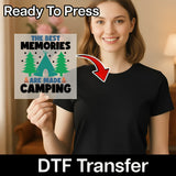 A woman in a black shirt holds InkMerge's "The Best Memories Are Made Camping" DTF transfer. A red arrow highlights the design and “Ready To Press” appears at the top, ideal for your heat press projects.