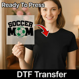 A woman holding a sign with the text "SOCCER MOM" and a red arrow pointing to her chest.