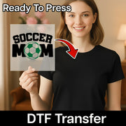 A woman holding a sign with the text "SOCCER MOM" and a red arrow pointing to her chest.