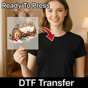 A woman in a black shirt holds an InkMerge Yule Log Cake Art DTF transfer sheet with holly and berries. “Ready To Press” is at the top and “DTF Transfer” at the bottom—ideal for custom apparel projects.