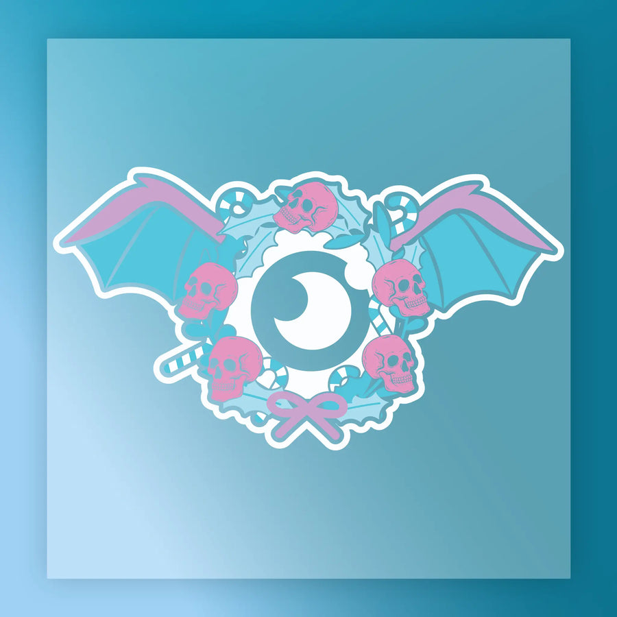 The InkMerge Gothic Pastel Skull Wreath showcases a central eye, blue bat wings, pink skulls, candy canes, and holly leaves with a pink bow on a blue gradient—ideal for DTF transfers.