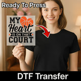 A woman holding a sign with the text "MY HEART IS ON THAT COURT" and a red arrow pointing to her chest.