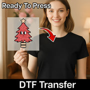 A smiling woman in a black shirt holds an InkMerge Kawaii Christmas Tree Design DTF transfer with cartoon eyes. An arrow points to her shirt. Text reads “Ready To Press” and “custom apparel DTF Transfer.”.