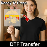 A smiling woman in a black shirt holds an InkMerge "Take a Hike Vintage Mountain - Heat Press Ready" DTF transfer sheet. The image includes “Ready To Press” and “DTF Transfer”—perfect for your next heat press project.