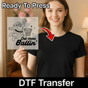 A woman is holding up a sign with a basketball graphic and the text "Out there Ballin'".