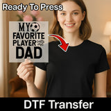 A smiling woman holding a sign that says "MY FAVORITE PLAYER calls me DAD" with a red arrow pointing to the sign.