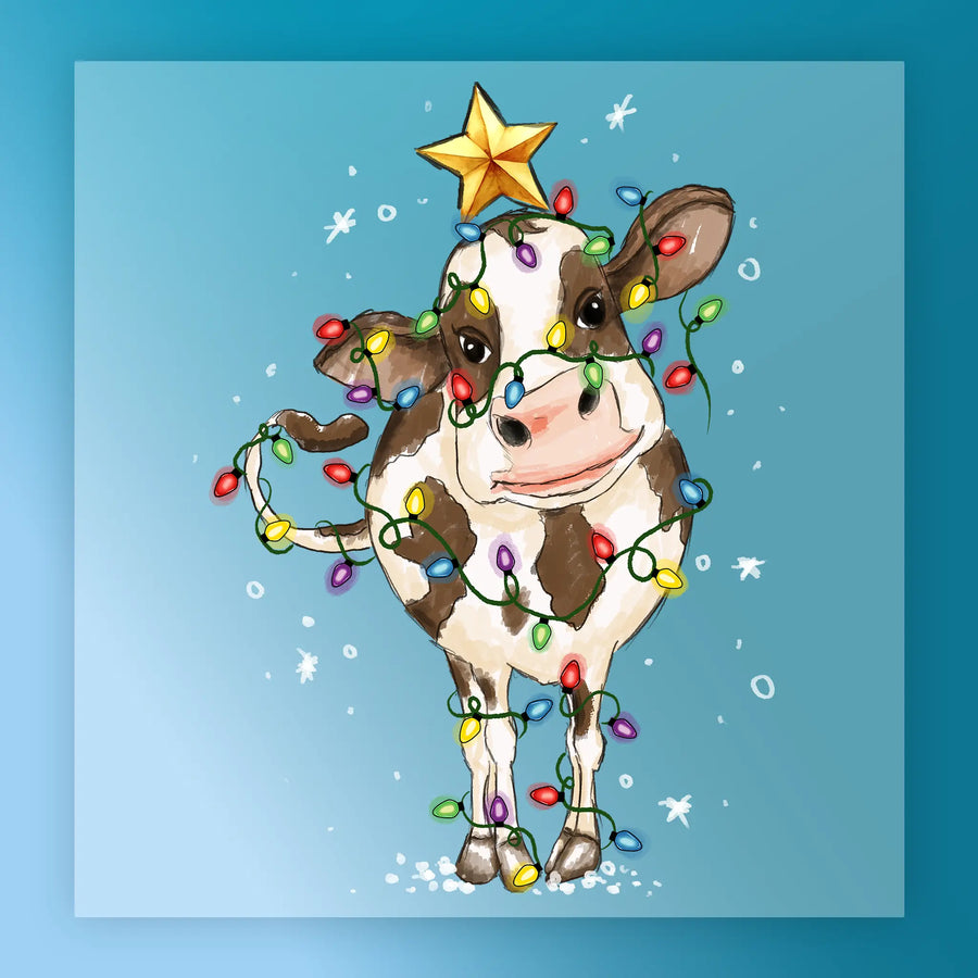 The InkMerge Funny Christmas Cow In Lights - Heat Press Ready features a cow standing on snow, wrapped in colorful bulbs with a yellow star on its head. Ideal for custom apparel with its blue background and festive falling snowflakes design.